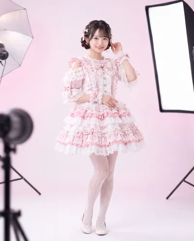 Rino on a photo set in a pink costume beside a softbox light